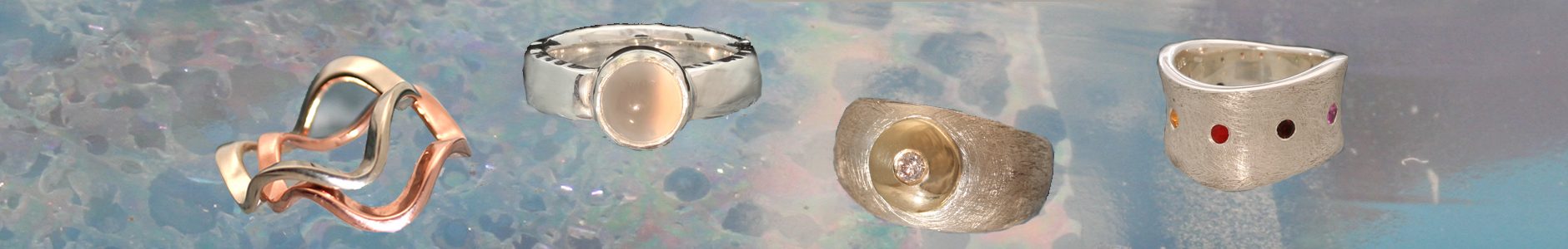 Een witgouden golfring en een roodgouden golfring, die tegen elkaar gedragen kunnen worden, een zilveren ring met een maansteen, een ijsmatte kogelring met een geelgouden schijfje met hierin een champagnekleurige briljant gezet, een gegolfde ring met rondom stenen gezet in de chakrakleuren.