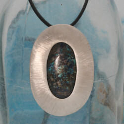 Een matte zilveren hanger met een ovale shattuckiet. Hoogte 6 cm. Exclusief collier.
Prijs: €265,- Shattuckiet