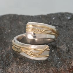 Een open zilveren ring met gewikkelde geelgouden draden