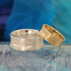 Een gouden en een zilveren trouwring met vingerafdrukken