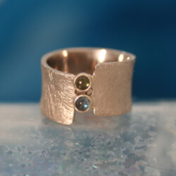 De kleuren van de toermalijnen zijn de kleuren van de ogen van de kinderen. Witgouden ring met een groene en een blauwe toermalijn