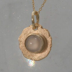 Een geelgouden matte hanger met een ronde maansteen, de doorsnede is 12 mm. De prijs is exclusief collier. Prijs: €310,-