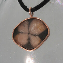 Een roodgouden hanger met chiastolith, ook wel cross-stone genoemd.