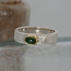 Een matte zilveren ring met een jade gezet in een geelgouden zetkastje