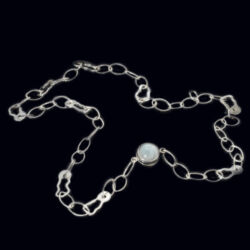 Een zilveren collier met fantasie schakels en een magneetslot met maansteen. De lengte is 59 cm. Hij kan ook drie maal om de arm als armband gedragen worden. Maansteen