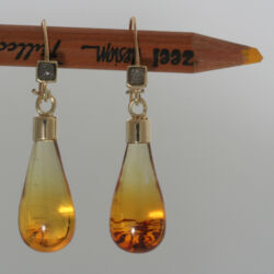 Geelgouden oorhangers met barnsteen druppels en ruwe diamanten.