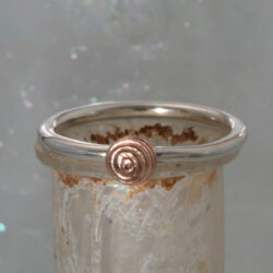 Een zilveren ring met een roodgouden knopje (5mm). De ring kan als aanschuifring gecombineerd worden. Prijs: €195,-