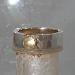 Een zilveren aanschuifring met een maansteen gezet in een geelgouden zetkastje. Breedte 6 mm
Prijs: €525,-