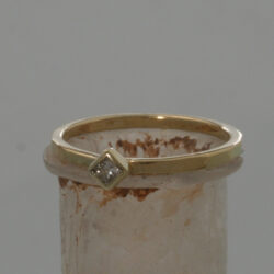 De band van deze geelgouden ring is hamerslag afgewerkt. De princess geslepen diamant van 0.10 crt ( 2,5 x 2,5 mm) zit in een glad zetkastje. De ring kan als aanschuifring gecombineerd worden. Prijs: €700,- Aanschuifringen