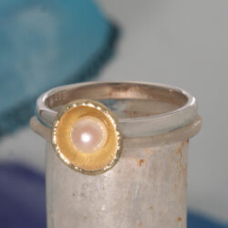 Een zilveren ring met een geelgouden schoteltje met een cultivé parel. De ring kan als aanschuifring gecombineerd worden. Prijs: €315,-
