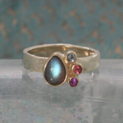 Geelgouden ring met een druppelvormige labradoriet met kleine blauwe topaas, roze toermalijn en amethyst