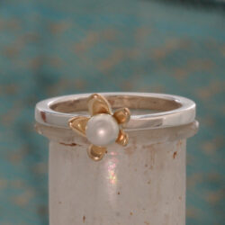 Zilveren ring met een geelgouden bloem met een zoetwaterparel. De ring kan als aanschuifring gecombineerd worden. Prijs: €315,-