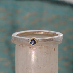Een zilveren ring met een saffier, gezet in een geelgouden zetting. De ring kan als aanschuifring gecombineerd worden. Prijs: €345,-