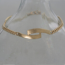 Een gouden armband, ijsmat en glanzend.