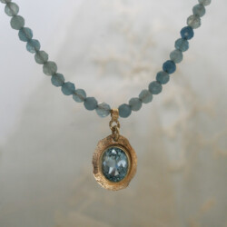 Collier van aquamarijn kralen met een geelgouden hanger met blauwe topaas.
