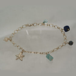 Geïnspireerd door strand en zee. Zilveren armband met amazoniet, kyaniet, lapis lazuli, topaas druppel, zoetwaterparel en een zilveren zeester. Prijs: €215,-