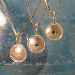 Goud en zilveren hangers, briljant, saffier en smaragd, ieder kind één.