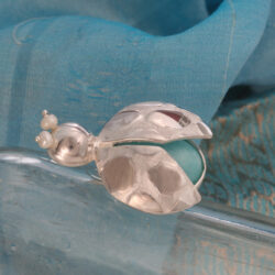 De luipaard-kever leeft op de oevers van de Amazone, Zuid-Amerika. Het is mag graag zwemmen. Als je goed luistert kun je het zacht horen bubbelen. De broche is gemaakt van zilver, amazoniet en zoetwaterparels. Lengte  33 mm
Prijs € 270,-