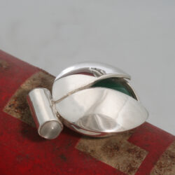 De malachiet-kever is een echt Afrikaans insect. Het houdt van zon en warmte. Soms komt hij voor in Nederland, dan heeft hij zich in een koffer verstopt. De hanger is gemaakt van zilver, malachiet en maansteen. Lengte 26 mm
Prijs € 245,-